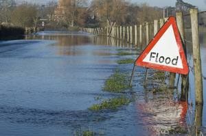 flooded road with a flood sign to the right of the photo